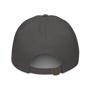 May include: A charcoal gray baseball cap with a curved brim. The back features an adjustable strap with a metal buckle for a custom fit. The cap is made of a soft, durable fabric.