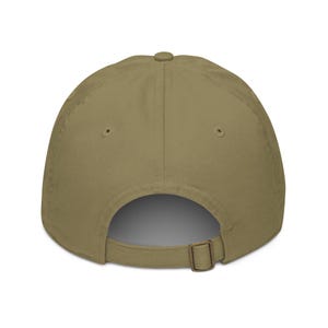 May include: A khaki-colored baseball cap, viewed from the back, featuring a curved brim and an adjustable metal buckle closure. The cap is made of a solid, neutral-toned fabric, suitable for various outfits.