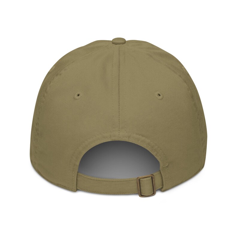 May include: A khaki-colored baseball cap, viewed from the back, featuring a curved brim and an adjustable metal buckle closure. The cap is made of a solid, neutral-toned fabric, suitable for various outfits.