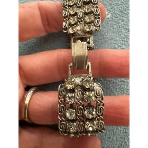 Peut inclure: Un bracelet en métal argenté présentant un design à plusieurs rangées avec des strass ronds et transparents sertis dans des maillons en filigrane torsadé et un fermoir rectangulaire à cliquet au centre.