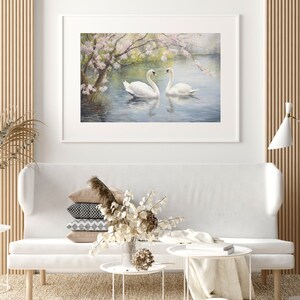 May include: A framed painting of two white swans swimming in a lake with a blooming tree in the background.