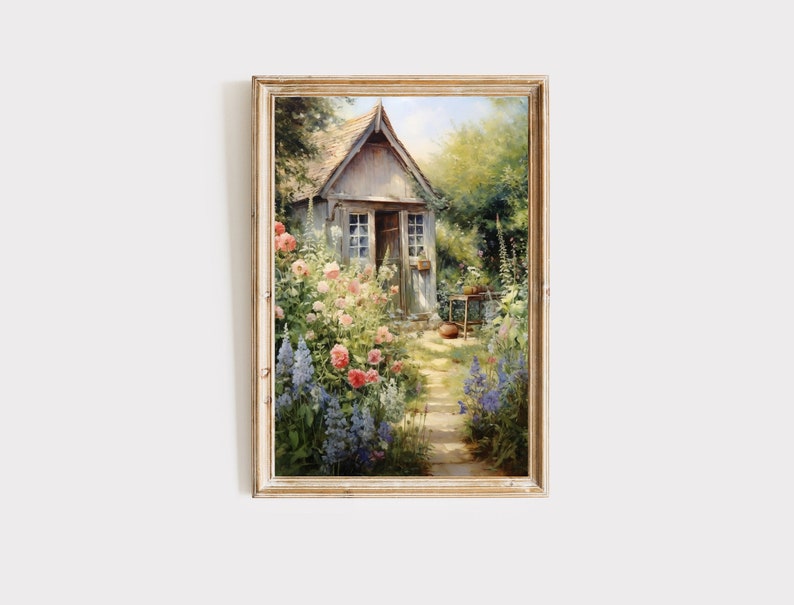 May include: A framed painting of a cottage with a garden path leading to the front door. The cottage is surrounded by lush greenery and colorful flowers, including pink roses and blue delphiniums.