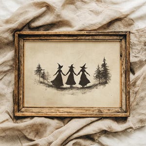Könnte beinhalten: Ein rechteckiger Holzrahmen mit einem beigen Druck von drei Figuren in spitzen Hüten und langen Kleidern, die sich an den Händen halten. Die Figuren sind zwischen zwei Kieferngruppen platziert, alles als Illustration in schwarzer Tinte.