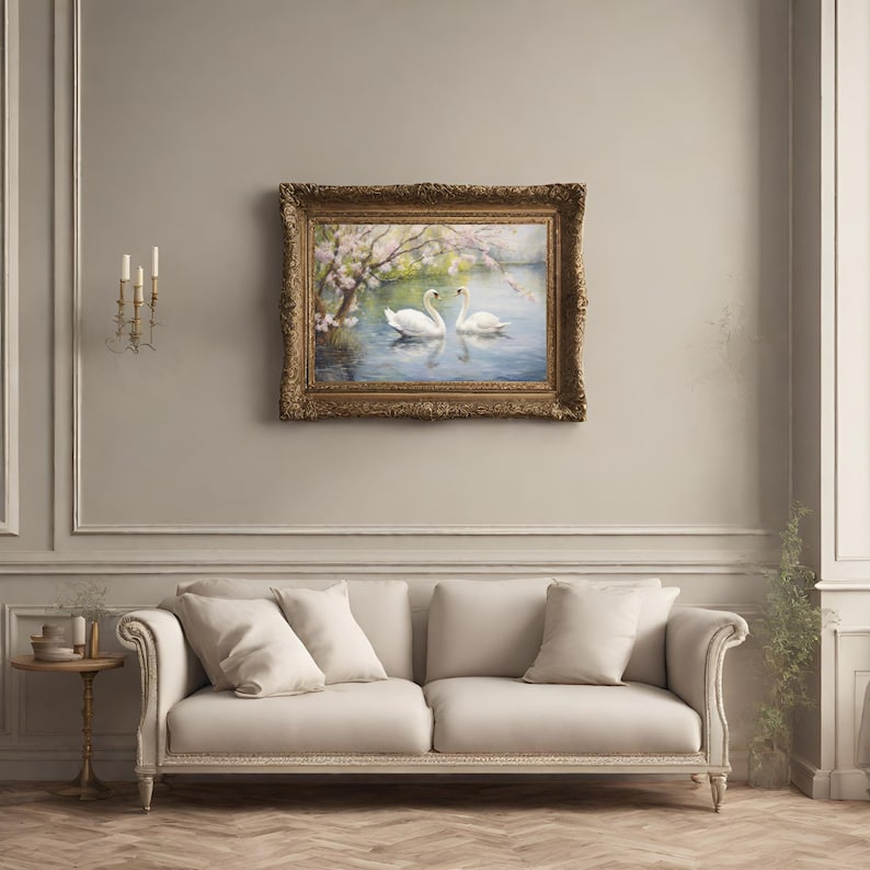 May include: A framed painting of two white swans swimming in a lake with a blooming tree in the background. The frame is ornate and gold.