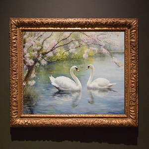 May include: A framed painting of two white swans swimming in a lake with a blooming tree in the background. The painting is in a gold frame with ornate details.