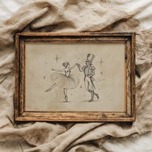 Könnte beinhalten: Ein rechteckiger Holzrahmen mit einem beigen Druck, der eine schwarze Strichzeichnung einer Ballerina im Tutu zeigt, die mit einem Nussknacker-Soldaten tanzt. Die Illustration enthält kleine Sternakzente um die beiden Figuren herum.