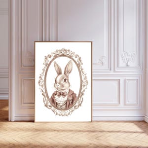 May include: A brown rabbit wearing a brown jacket with a white collar and a bow tie, in a gold ornate frame on a white background.