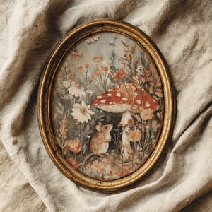 Op de afbeelding: Ovaalvormig ingelijst kunstwerk met een grillige bosscène. Een rood-witte paddenstoel domineert het midden, met een kleine muis en diverse bloemen. De lijst is goudkleurig met een verweerde afwerking.