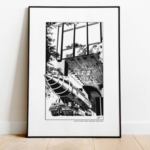 May include: Black and white illustration print of a rocket-like vehicle with a pointed front, parked under a building with large windows. The print is framed in a black frame. Text at the bottom reads "Fighting Fantasy Robot Commando Robot Robot".