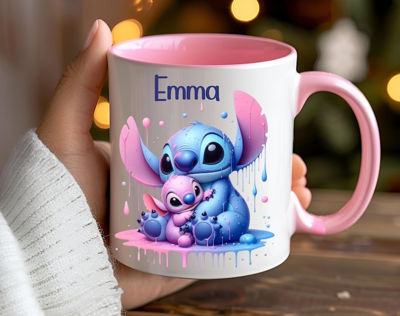 K&ouml;nnte beinhalten: Eine wei&szlig;e Keramiktasse mit rosafarbenem Rand und Henkel. Die Tasse zeigt eine farbenfrohe Illustration von Stitch und Angel aus dem Disney-Film Lilo & Stitch. Die Tasse ist mit dem Namen "Emma" personalisiert.