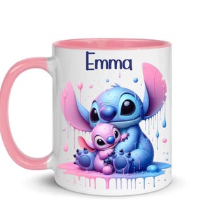 K&ouml;nnte beinhalten: Eine wei&szlig;e Keramiktasse mit rosafarbenem Rand und Henkel. Die Tasse zeigt eine farbenfrohe Illustration von Stitch und Angel aus dem Disney-Film Lilo & Stitch. Der Text "Emma" ist auf die Tasse gedruckt.