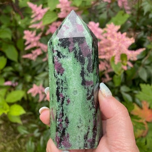 Op de afbeelding: Een groene, zwarte en roze zultanite kristallen punt. De kristal is gefacetteerd en heeft een puntige punt.