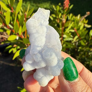 Może przedstawiać: Gromada niebieskiego chalcedonu o powierzchni z bąbelkami i fakturą. Chalcedon ma jasnoniebieski kolor i jest półprzezroczysty.