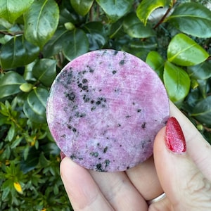 Op de afbeelding: Een ronde, roze en zwarte gepolijste steen met een gevlekt patroon.