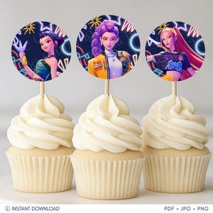 Op de afbeelding: Drie cupcakes met karaktertoppers. De toppers tonen vrouwen met kleurrijk haar en kleding, tegen een donkere achtergrond met neonaccenten. De cupcakes zijn versierd met witte frosting.