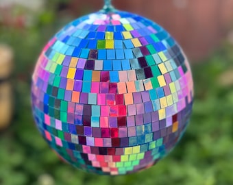 May include: A multi-colored disco ball with iridescent mirrored tiles. The ball is hanging from a chain.