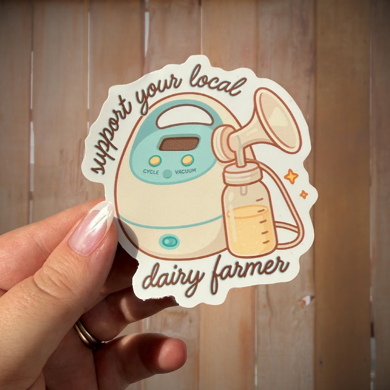 May include: A sticker with a cartoon breast pump illustration and the text "support your local dairy farmer." The pump is beige and teal, with a milk bottle. The sticker is held by a hand.