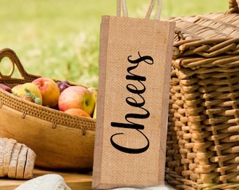 May include: A brown burlap wine bottle bag with a black rope handle and the word "Cheers" printed in black on the front.