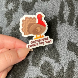 May include: A white sticker with a cartoon turkey illustration and the text "Cornbread knows my sins".