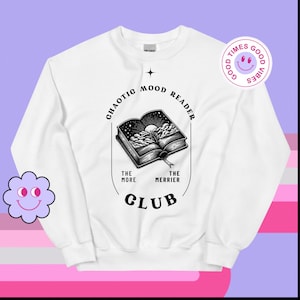 Könnte beinhalten: Weißer Pullover mit einem schwarzen Grafikdesign eines offenen Buches mit Wolken und einem Mond. Der Text um das Buch lautet "Chaotic Mood Reader" und "The More The Merrier Club".