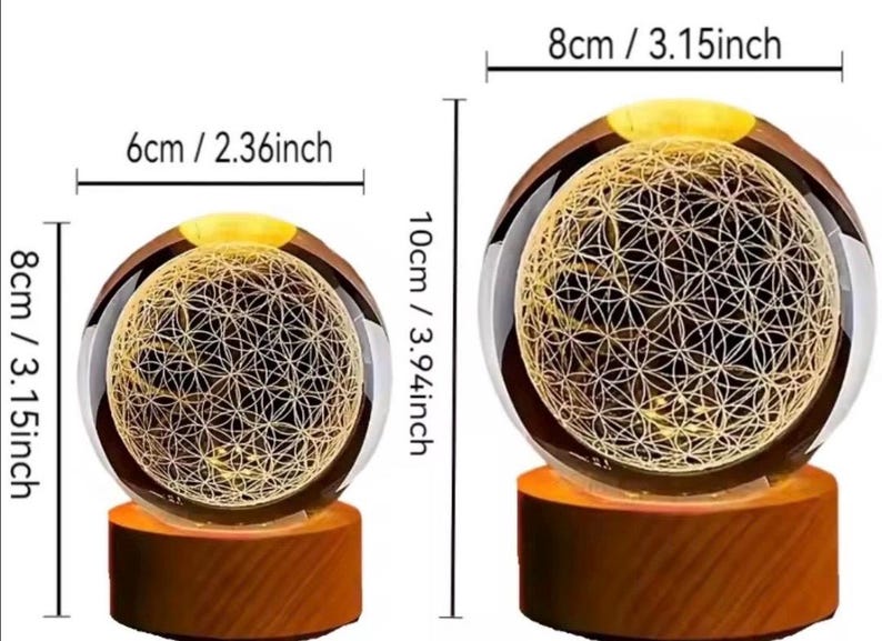 May include: Two spherical glass lamps with an internal laser-etched flower of life pattern, illuminated by warm light. The smaller lamp is 2.36 inches wide and 3.15 inches tall. The larger lamp is 3.15 inches wide and 3.94 inches tall on wooden bases.