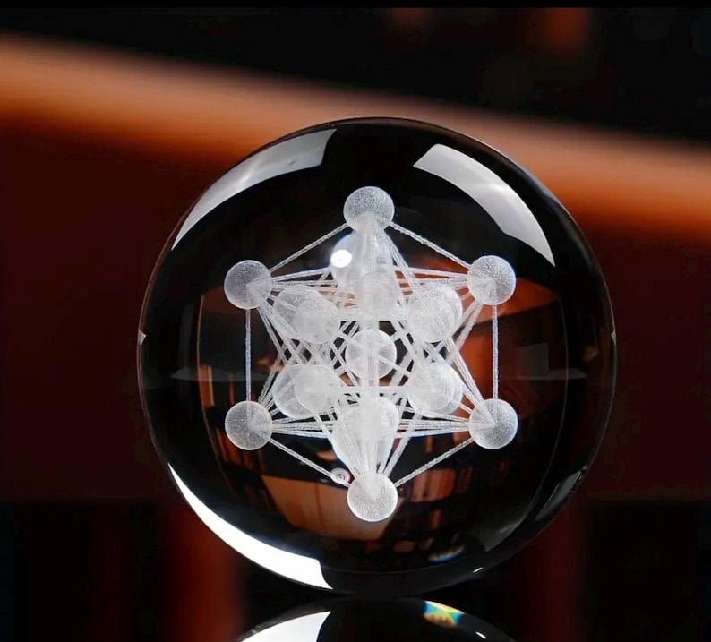 May include: A clear glass sphere featuring an internal laser-etched white geometric pattern known as Metatron's Cube. The design consists of multiple interconnected spheres and straight lines, creating a complex three-dimensional structure.