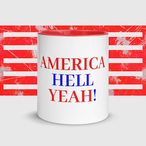 May include: White ceramic mug with a red interior and the words "AMERICA HELL YEAH!" in red and blue lettering. The background features a red and white design reminiscent of the American flag.