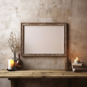 May include: A rustic wooden frame with a blank white canvas hangs on a textured beige wall.  Two glass bottles, one with a candle inside, and a stack of books are on a wooden table in front of the frame.