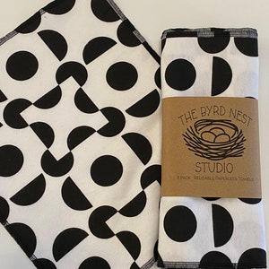 May include: Two black and white geometric patterned kitchen towels with black stitching. The towels are folded and the top towel has a brown label that reads "The Byrd Nest Studio 8 Pack - Reusable Paperless Towels".