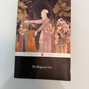May include: A Penguin Classics edition of "The Bhagavad Gita" book. The cover features a colorful illustration of a group of people in traditional Indian attire. The book has a black spine and the title is printed in white.