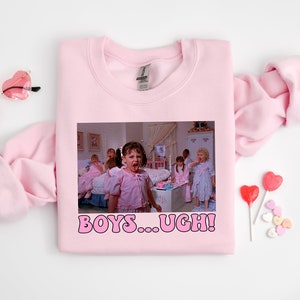 May include: Pink sweatshirt with a graphic print of a scene from the movie "Mean Girls". The graphic shows a group of girls in pajamas with the text "BOYS...UGH!" printed below.