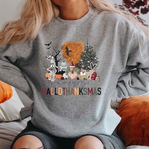 Puede incluir: Sudadera gris con un dise&ntilde;o gr&aacute;fico colorido que presenta un esqueleto, calabazas, un pavo, un &aacute;rbol de Navidad y el texto "Happy Hallothanksmas".
