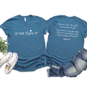May include: Teal t-shirt with the text "GET YOUR Hopes UP" and a small heart. The back of the shirt has a Bible verse printed in white. A pair of white sneakers and blue jeans are also in the image.