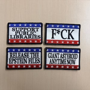 May include: Four rectangular embroidered patches with a red, white, and blue border featuring white stars. The patches contain the text: SUPPORT PUBLIC LIBRARIES, F*CK, RELEASE THE EPSTEIN FILES, and GIANT ASTEROID ANYTIME NOW in black lettering.