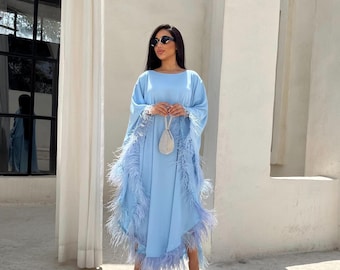 May include: A light blue maxi dress with feather trim on the sleeves and hem. The dress has a loose, flowing fit and is perfect for a summer occasion.