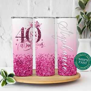 May include: Three stainless steel tumblers with pink glitter and a pink ombre design. The tumblers feature the text "40 & fabulous" and a crown on one tumbler, and the name "Stephanie" on another tumbler.