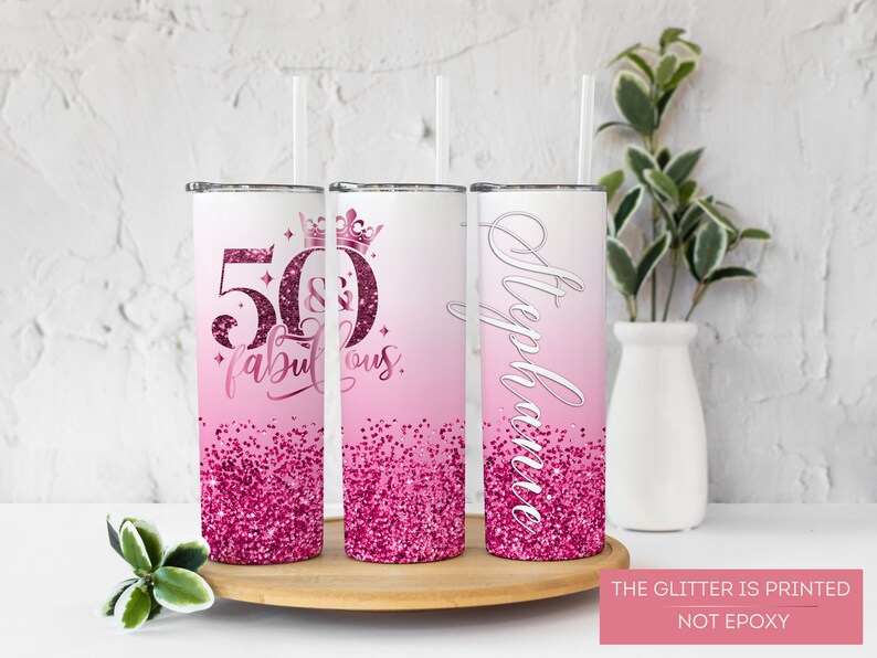 May include: Three pink and white stainless steel tumblers with glitter accents. The tumblers feature the text "50 & Fabulous" and "Stephanie".