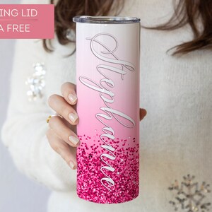 May include: A pink and white ombre stainless steel tumbler with a pink glitter design and the name "Stephanie" written in white cursive. The tumbler has a sliding lid and is BPA free.