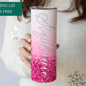 May include: A pink and white stainless steel tumbler with a pink glitter design and the name "Stephanie" written in white cursive. The tumbler has a sliding lid and is BPA free.