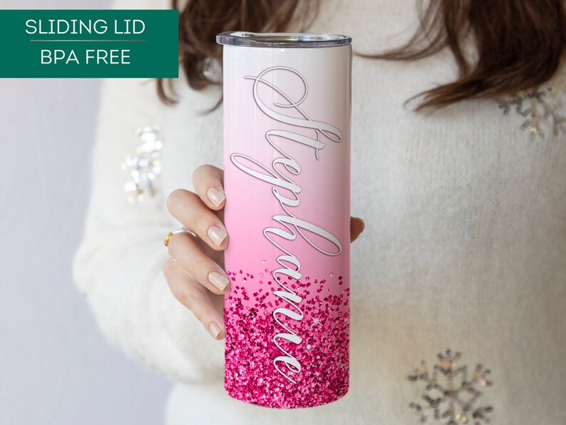 May include: A pink and white stainless steel tumbler with a pink glitter design and the name "Stephanie" written in white cursive. The tumbler has a sliding lid and is BPA free.