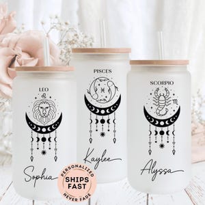 May include: Three clear glass tumblers with bamboo lids and straws. Each tumbler features a different zodiac sign: Leo, Pisces, and Scorpio. The tumblers are personalized with the names Sophia, Kaylee, and Alyssa.