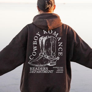 May include: Dark chocolate brown hoodie with a white graphic print of cowboy boots and the text "COWBOY ROMANCE READERS DEPARTMENT".