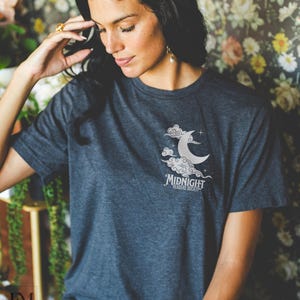 May include: Dark grey heather t-shirt with a white graphic of a crescent moon in clouds and the text "Midnight Readers Society".