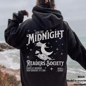 Może przedstawiać: Czarna bluza z kapturem z białym nadrukiem przedstawiającym p&oacute;łksiężyc i chmury. Tekst głosi "Join the Midnight Readers Society" i zawiera szczeg&oacute;ły "Starts at midnight, then suddenly it's 3 am. Bring a blanket."