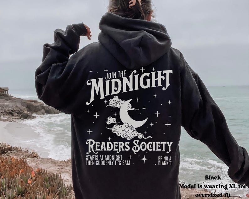 Może przedstawiać: Czarna bluza z kapturem z białym nadrukiem przedstawiającym p&oacute;łksiężyc i chmury. Tekst głosi "Join the Midnight Readers Society" i zawiera szczeg&oacute;ły "Starts at midnight, then suddenly it's 3 am. Bring a blanket."