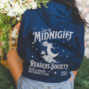 Może przedstawiać: Bordowy sweter z kapturem z białym nadrukiem, na którym widnieje napis "Join the Midnight Readers Society". Nadruk zawiera również półksiężyc i chmury. Tekst pod nadrukiem brzmi "Starts at midnight then suddenly it's 3am. Bring a blanket."