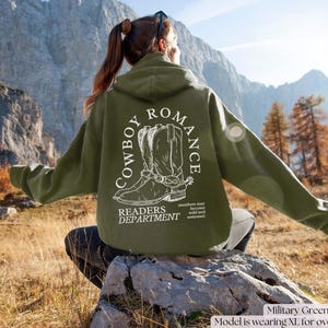 May include: A green hooded sweatshirt with a white graphic of cowboy boots and the text "COWBOY ROMANCE READERS DEPARTMENT". The text "members may become wild and untamed" is also included on the sweatshirt.