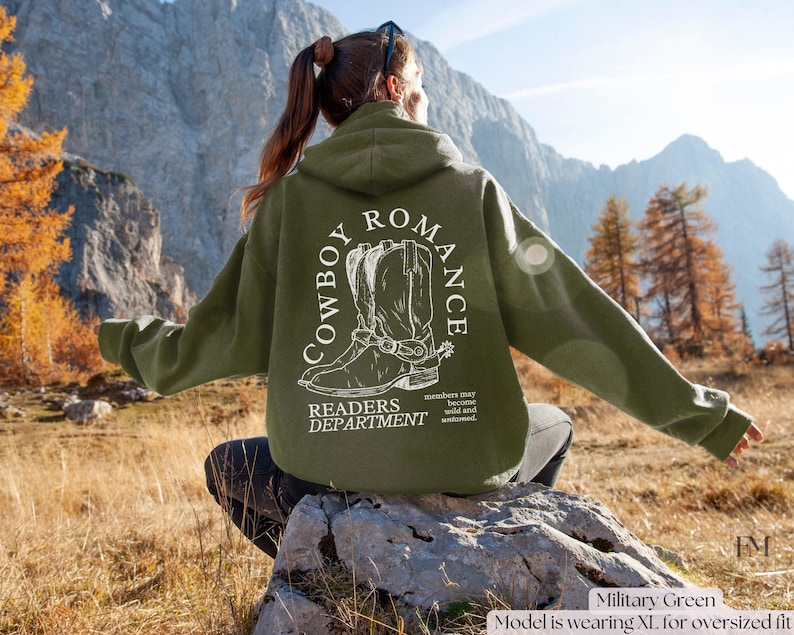 May include: A green hooded sweatshirt with a white graphic of cowboy boots and the text "COWBOY ROMANCE READERS DEPARTMENT". The text "members may become wild and untamed" is also included on the sweatshirt.