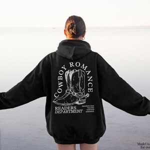 May include: Black hoodie with a white graphic print of cowboy boots and the text "Cowboy Romance Readers Department".