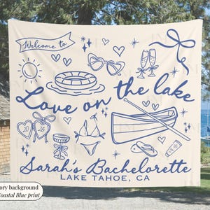 May include: Ivory banner with coastal blue illustrations and text. The banner reads "Welcome to Love on the lake" and "Sarah's Bachelorette Lake Tahoe, CA". The design includes hearts, sunglasses, champagne flutes, and a boat.